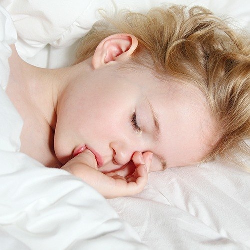 young girl sucking thumb while sleeping